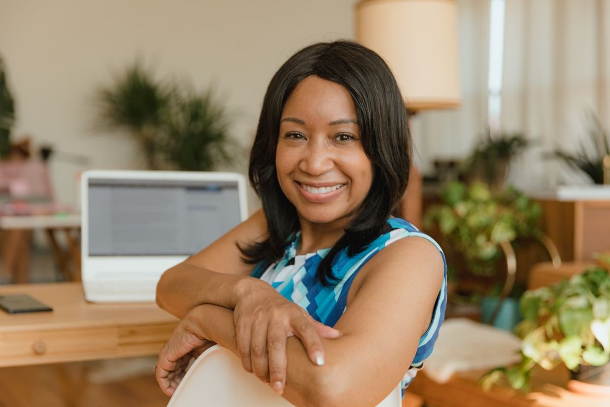 Smiling woman with arms crossed in a home office with plants