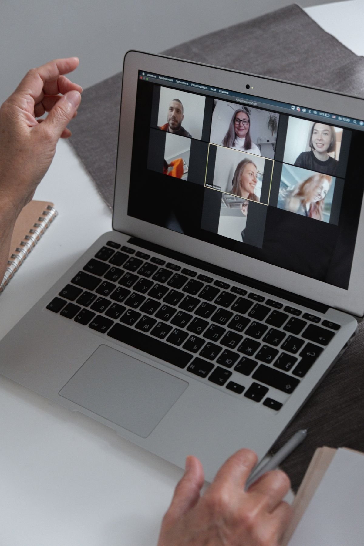 Laptop screen showing a team video call grid, held at home